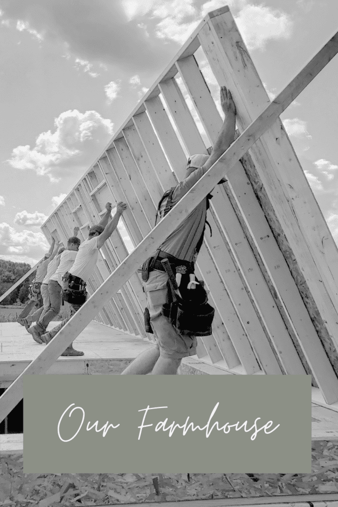 men are framing the wall of a house. Words say our farmhouse.